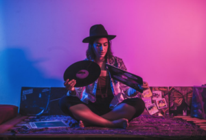 Musician hold vinyl in an environment with pink and blue light