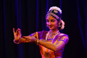Bharatanatyam dancer gestures with her arms forwards.