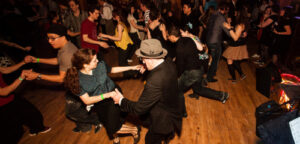 Multiple people in a ballroom dancing together in pairs.