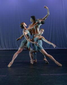 Four ballet dancers pose in a complex shape with elongated arms and legs.