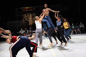 Bill T Jones/Arnie Zane Company members on stage lift up one company dancer in the center of the space.