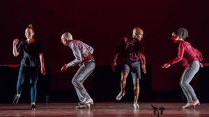 Four Dorrance dancers performing slightly hinged forward and with knees bent.