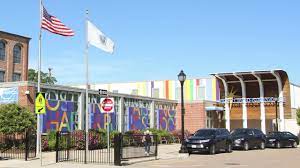 Photo of the outside of the school with MA flag and USA flag.