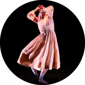 Elizabeth Epsen, performer, in a pink dress points toes in a coupé while bringing arms up over face.