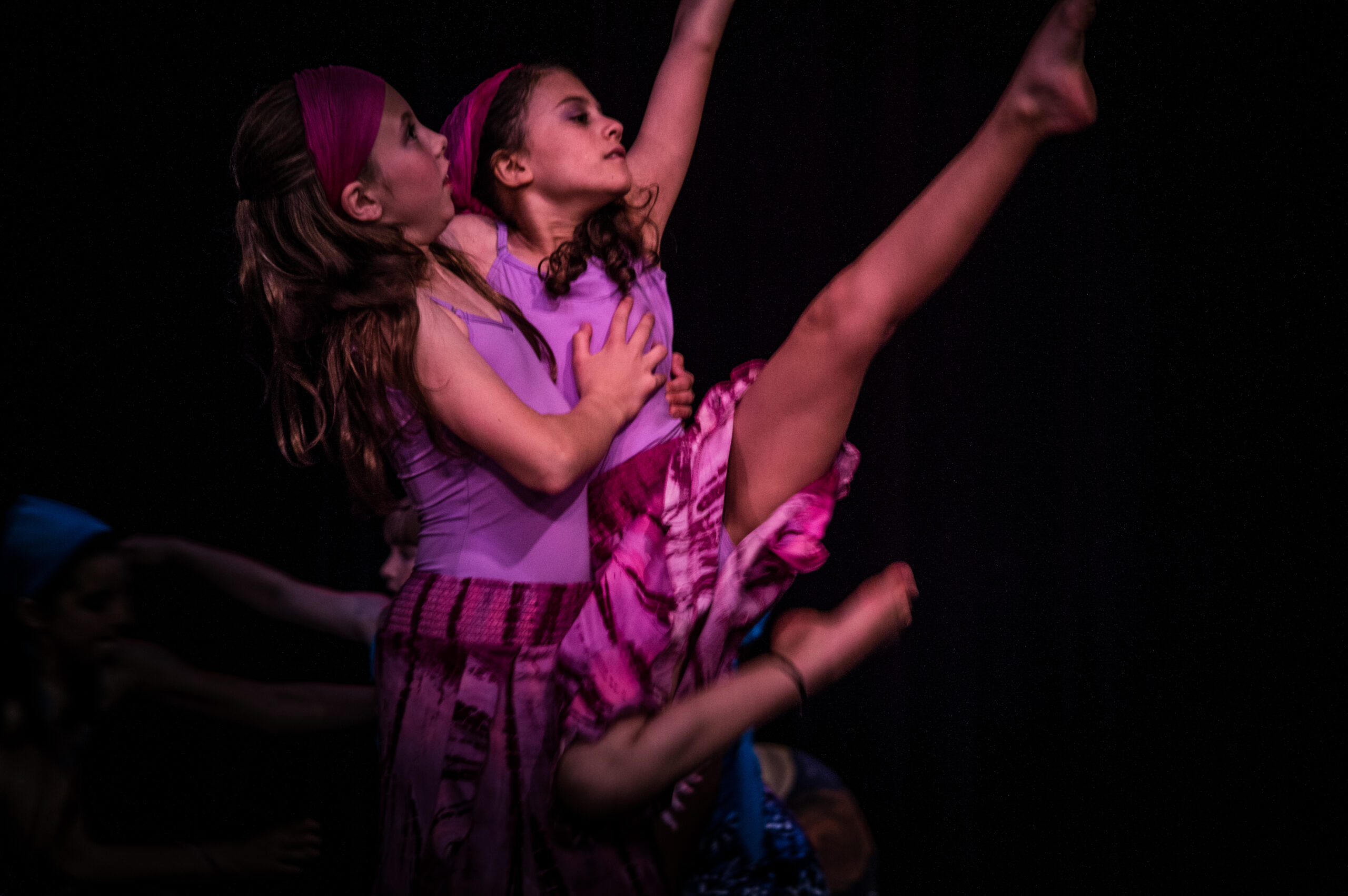 Two young dancers performing: one holds the other up in a weight sharing lift.