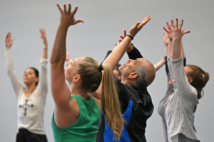 David Dorfman and students mid-movement with arms raised