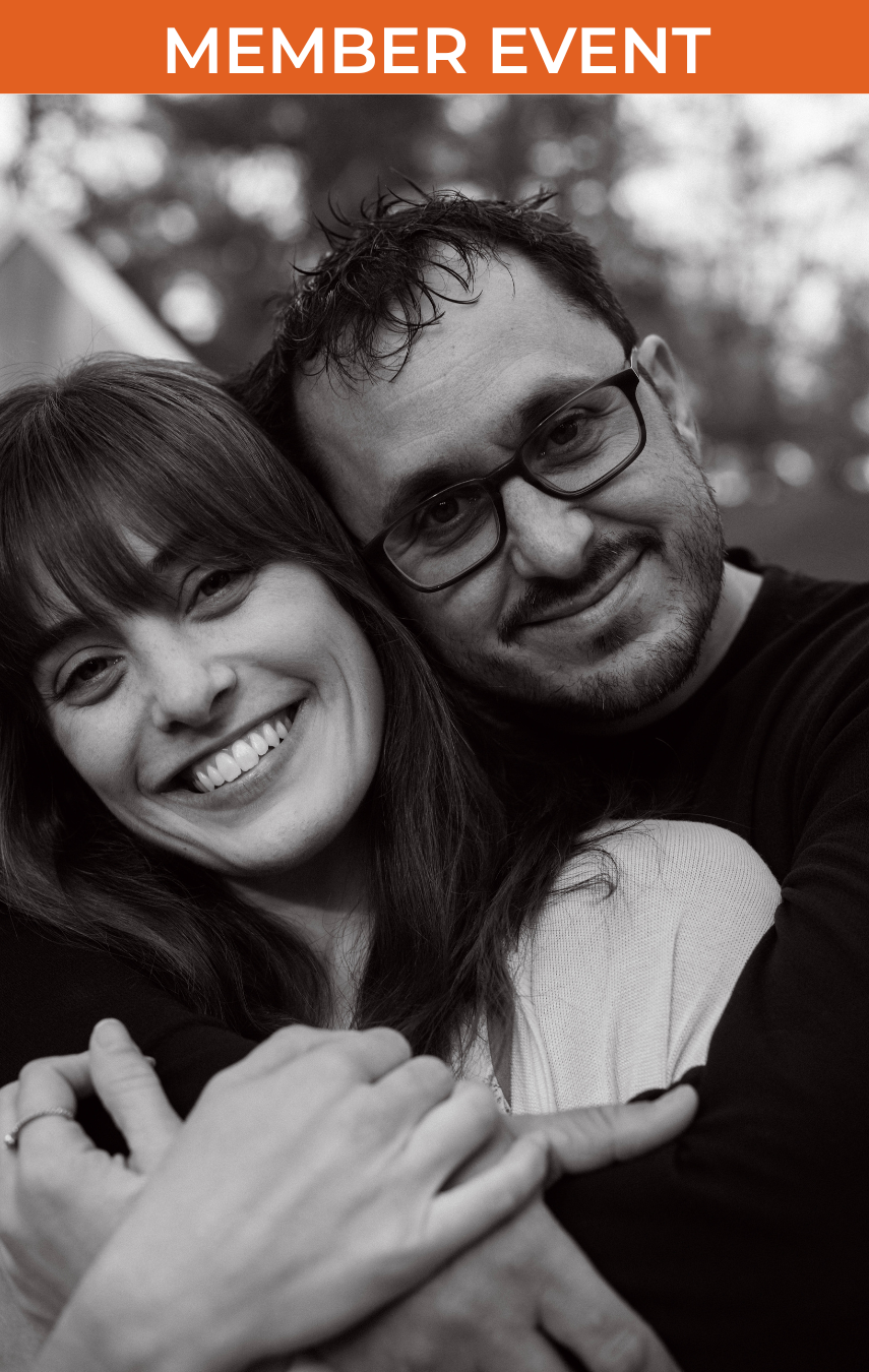 Black and white photo of woman and man embracing, both facing the camera and smiling
