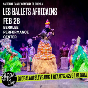 Les Ballets Africains dressed in vibrant traditional clothing dance on stage.