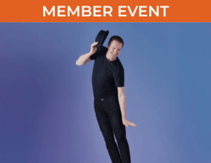 Man in black clothing holding hat in raised right hand in front of blue and purple background